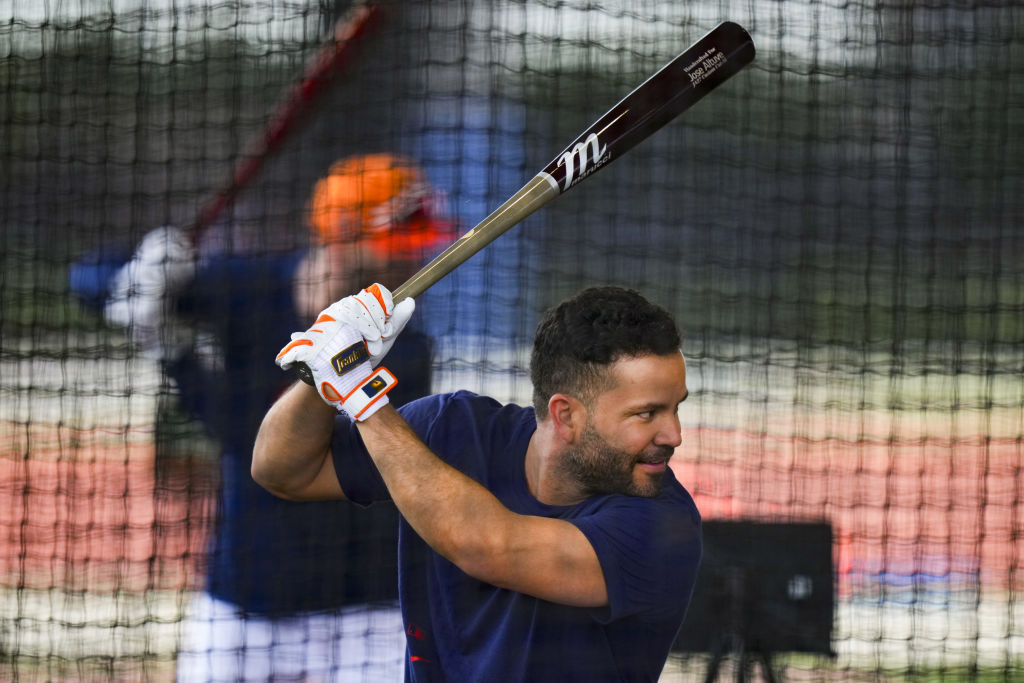A man in a batting cage gripping a baseball bat, ready to swing.