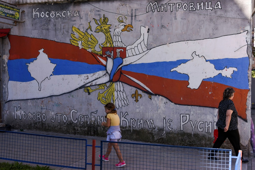 A child walks by a mural reading 'Kosovo is Serbia -- Crimea is Russia' in a Serb part of Mitrovica, Kosovo