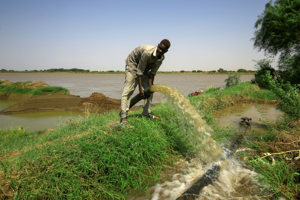 A farmer opens an irrigation pipe from the Nile in Sudan's Gezira state