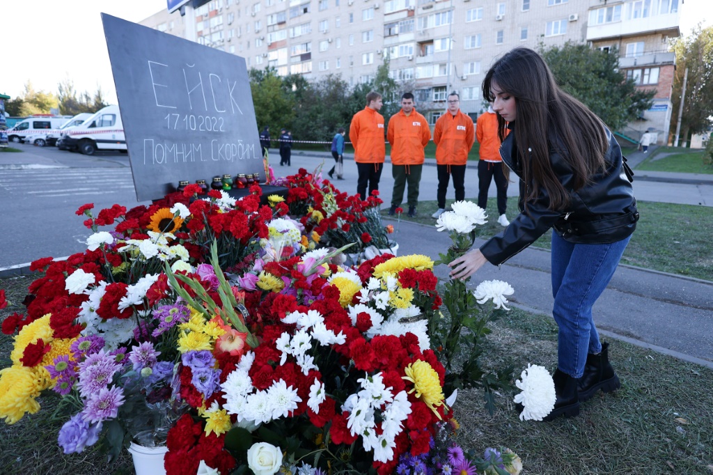 People lay flowers at a makeshift memorial for those killed after a Sukhoi Su-34 military jet crashed in the courtyard of a residential area in the town of Yeysk in southwestern Russia