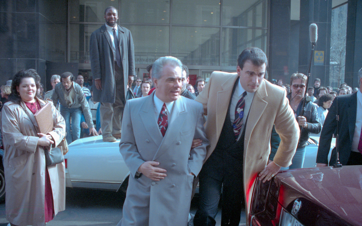 John Gotti (centre) is escorted by an unidentified man through the crowds outside court