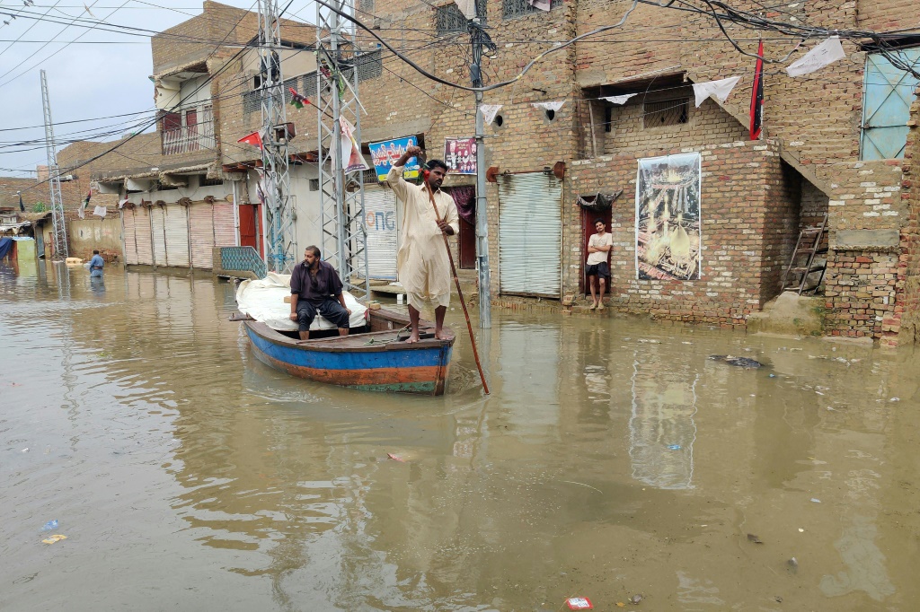 A resident makes his way by boat along a waterlogged street in Sukkur, Sindh province