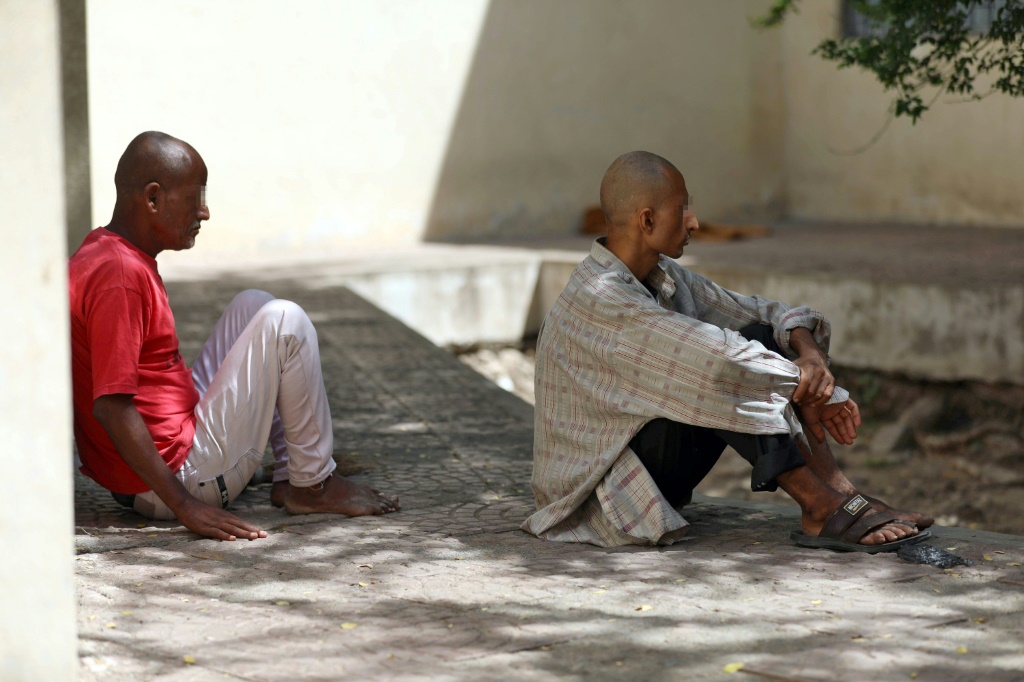 Patients at a psychiatric hospital sit outdoors in the shade in Yemen's third city of Taez