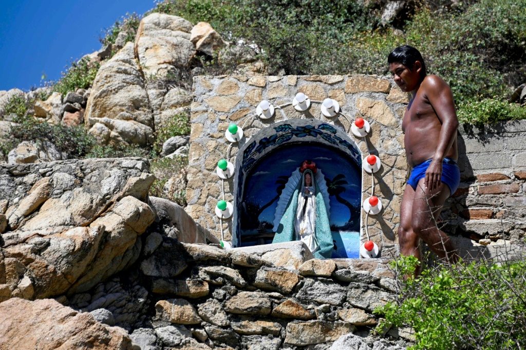 A cliff diver in Acapulco, Mexico walks past a shrine set up near the ledge where daredevils plunge into the Pacific