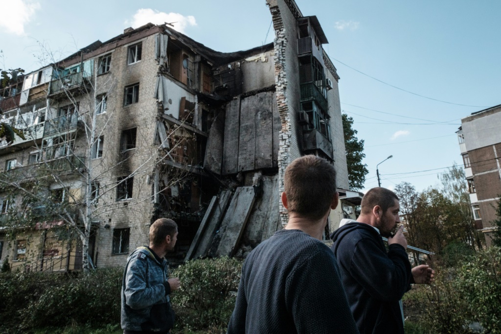 Residents of Bakhmut walk past destroyed residential buildings, with Russian forces advancing