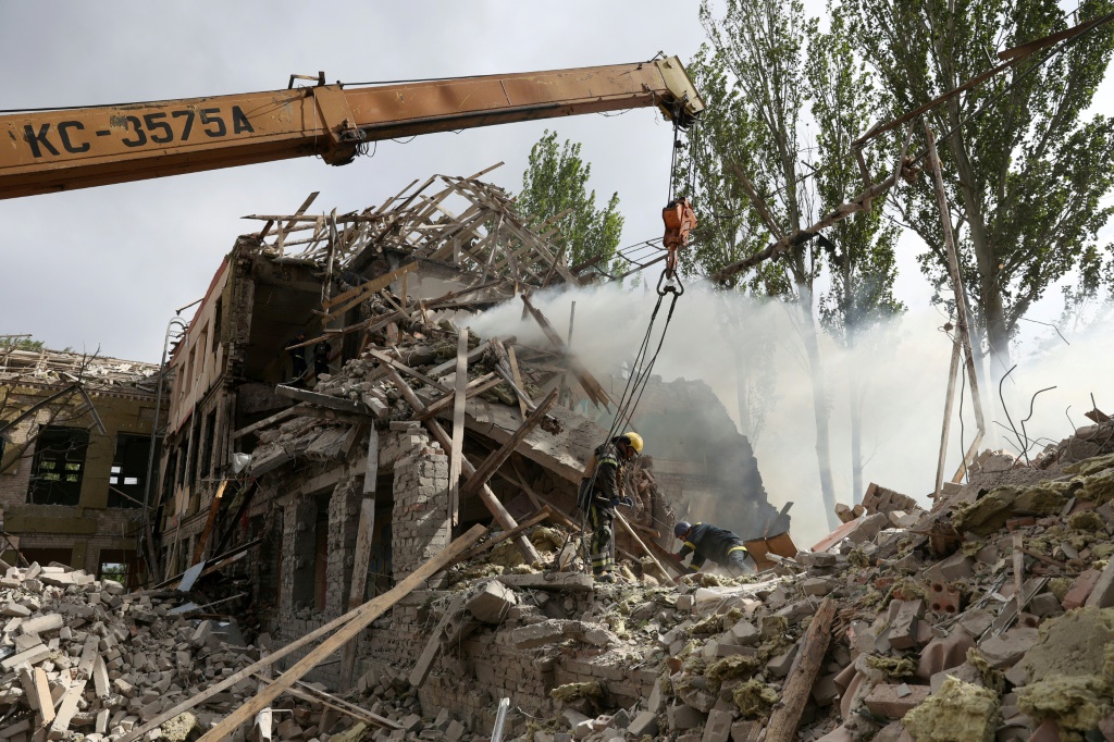 Ukrainian rescuers use a crane to move the debris out of a school building Kramatorsk