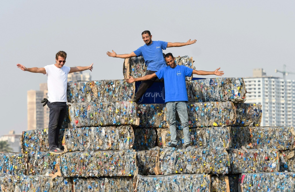 Environmental volunteers stand atop a pyramid of compressed plastic waste collected from the Nile, in Giza near the capital on "World Cleanup Day", September 17, 2022