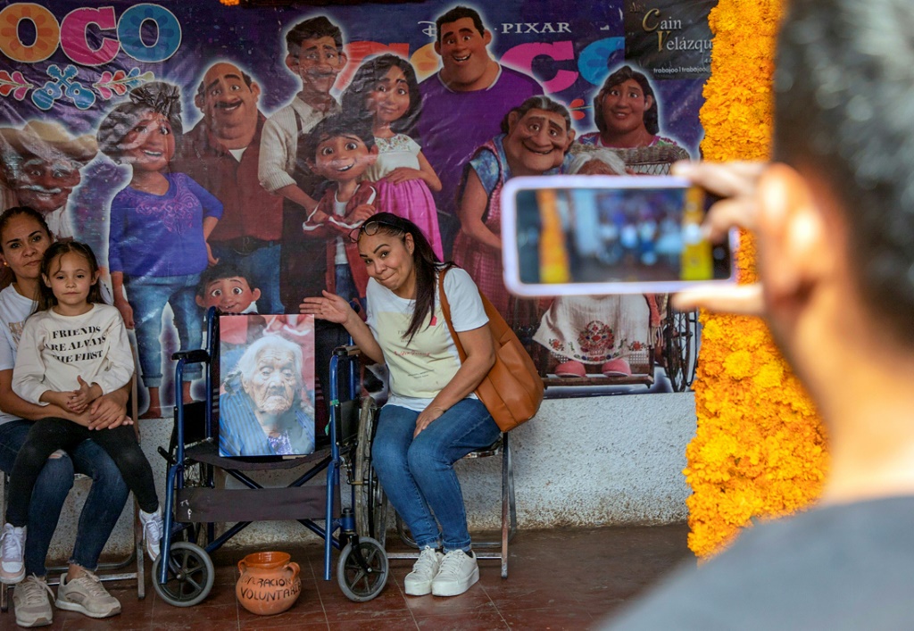Tourists pose for a picture at the home of Maria Salud Ramirez, believed by her family to be the inspiration for the animated movie character "Mama Coco"