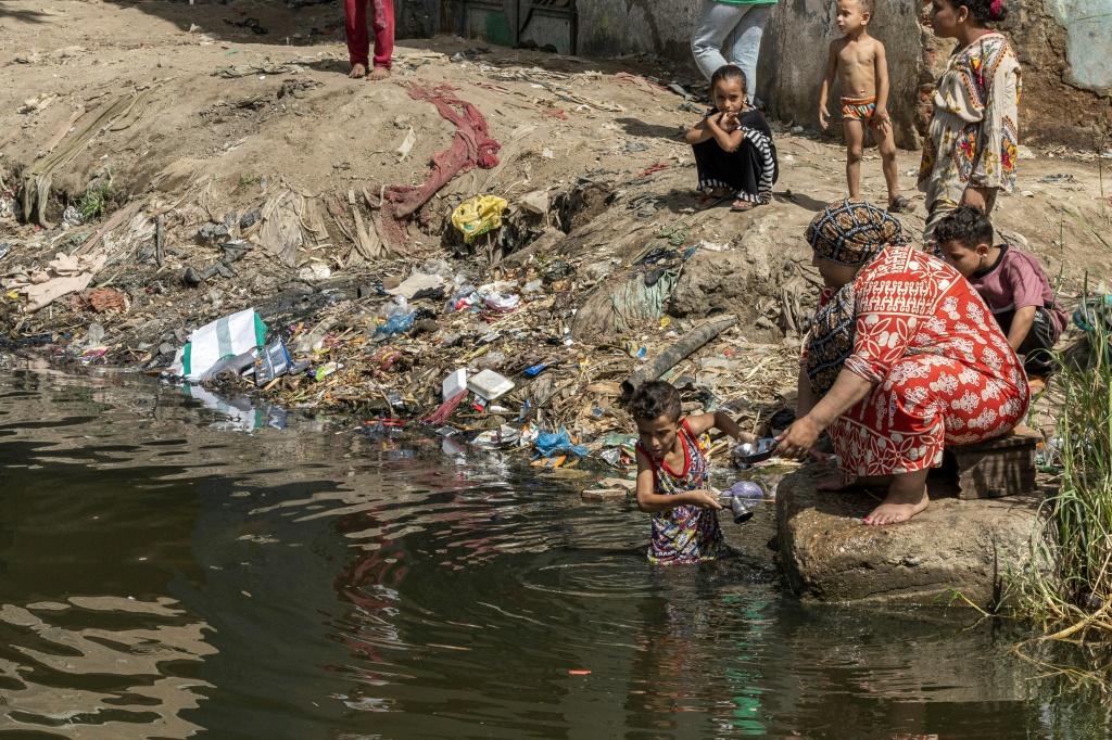 A child helps a woman wash pots in the Nile near Giza in Egypt