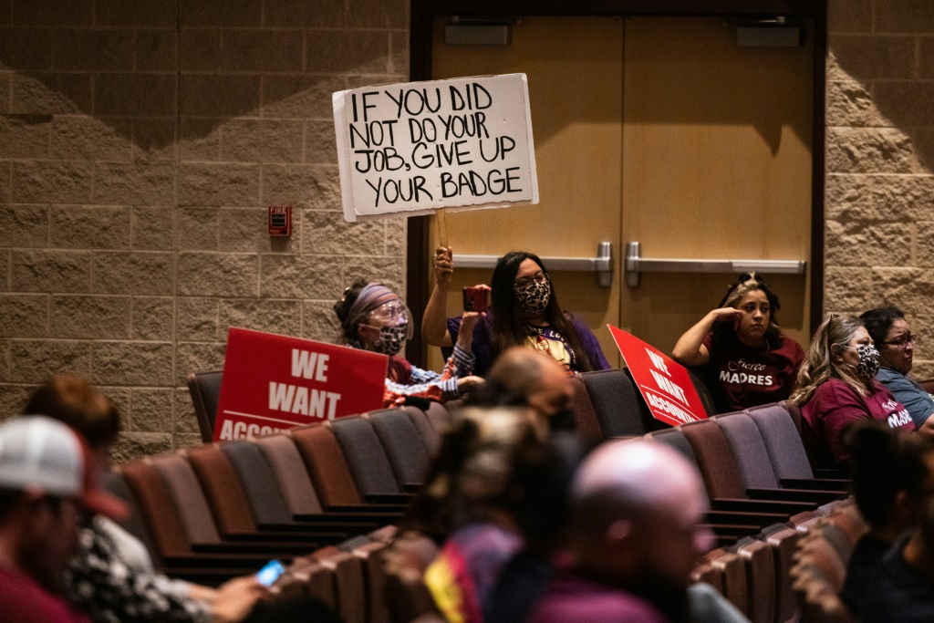 Attendees hold signs as the Uvalde Consolidated Independent School District Board holds a special meeting to consider the firing of Police Chief Pete Arredondo on August 24, 2022 in Uvalde, Texas