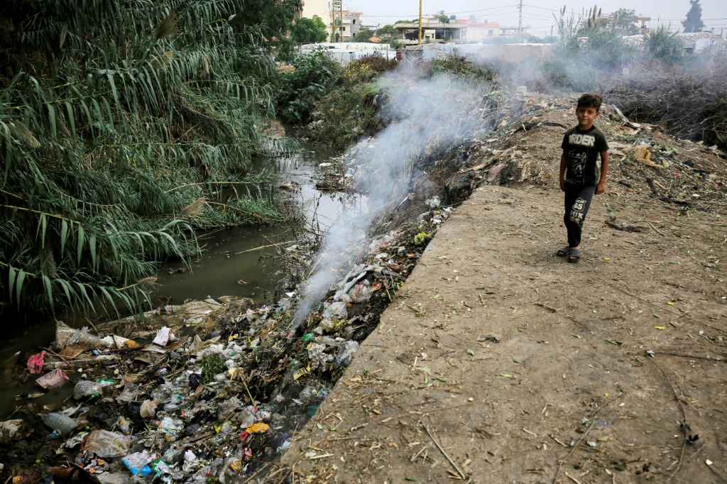 A child stands next to a polluted water source at a make-shift camp for Syrian refugees in Talhayat, near Bebnine, north Lebanon
