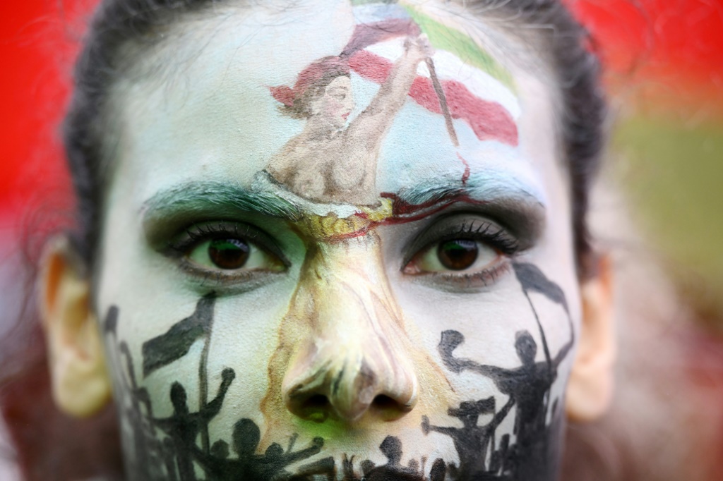 A protester wearing face-paint depicting France's iconic "Marianne" leading an uprising, attends a demonstration in support of Kurdish woman Mahsa Amini on October 2 in Paris
