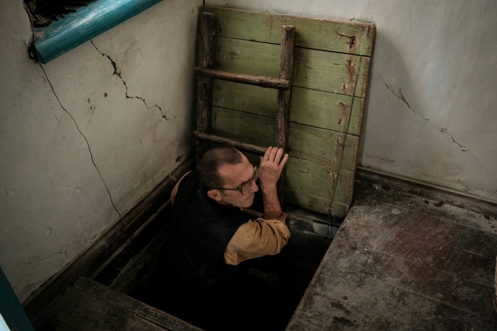 Ivan Lobachov emerges from a cellar used as a shelter, in the family house which was partially destroyed by shelling