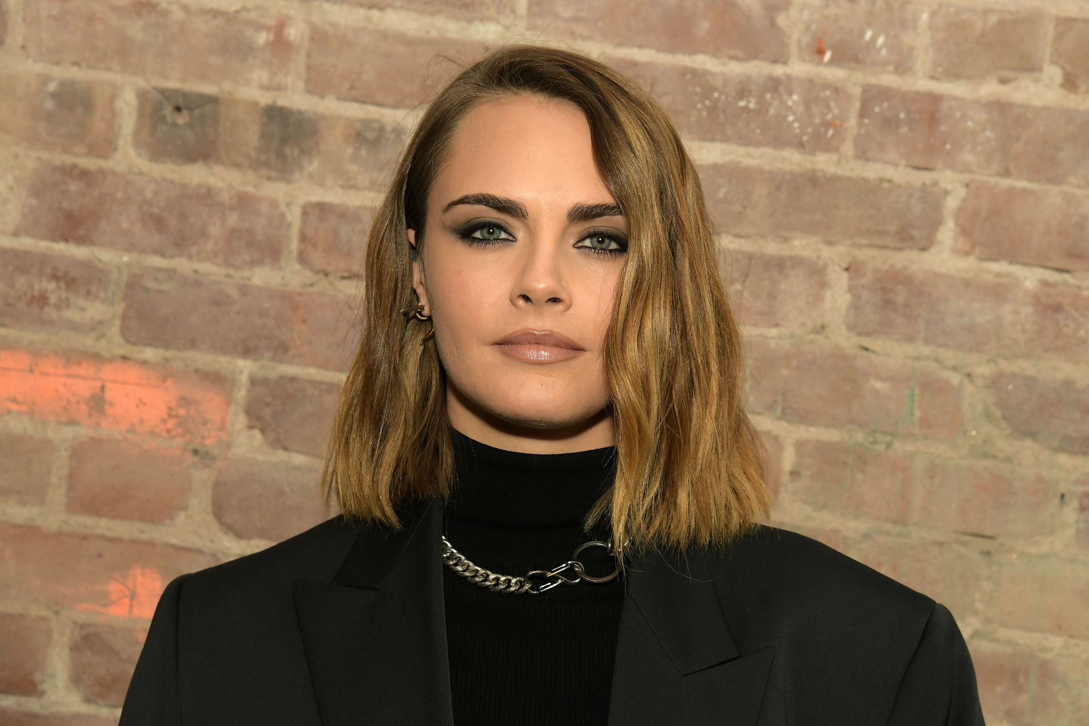 Cara Delevingne stands next to a wall in New York City, New York