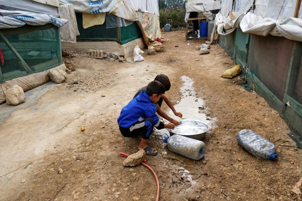 Amid an outbreak of cholera in the region, children rinse their hands at a camp for Syrian refugees in Talhayat, Lebanon