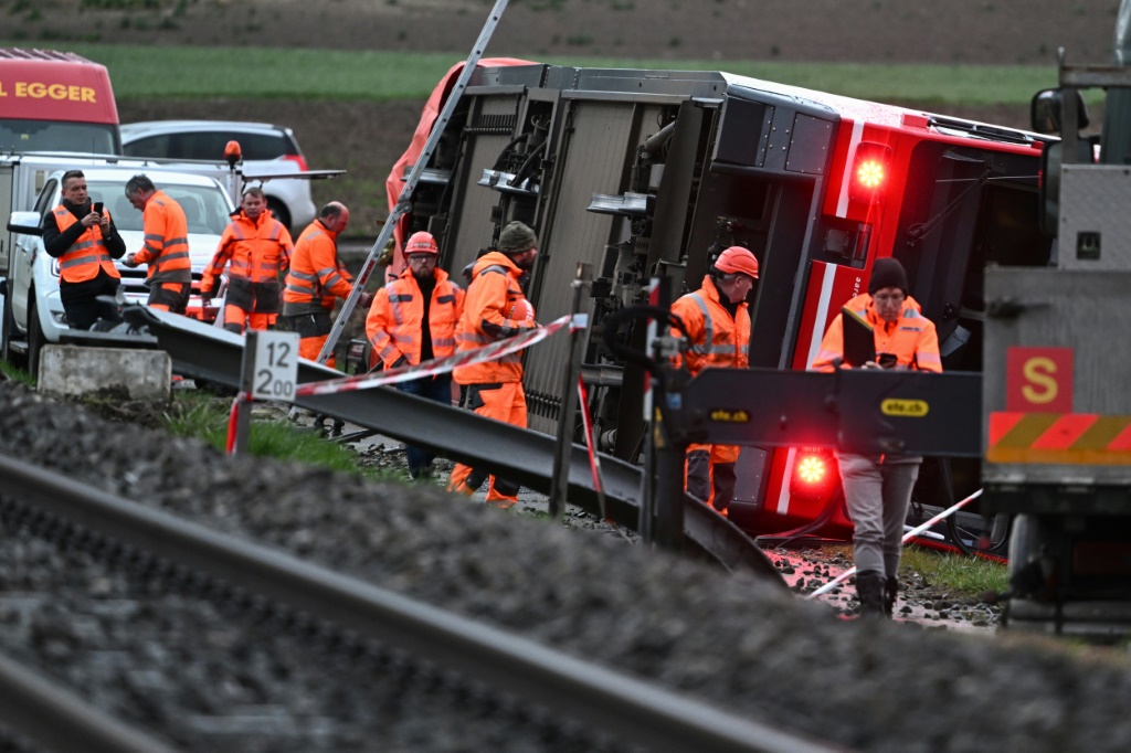 Train staff inspect the first derailment near the lakeside town of Luscherz, northwest of Bern