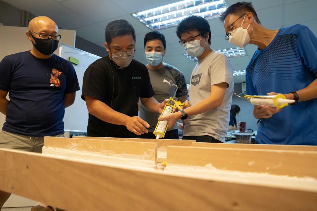 Lau Chun-yu (centre L), co-founder of Renobro, teaches caulking skills to students taking a home-repair class in Hong Kong -- he said he hadn't expected so many people would be emigrating
