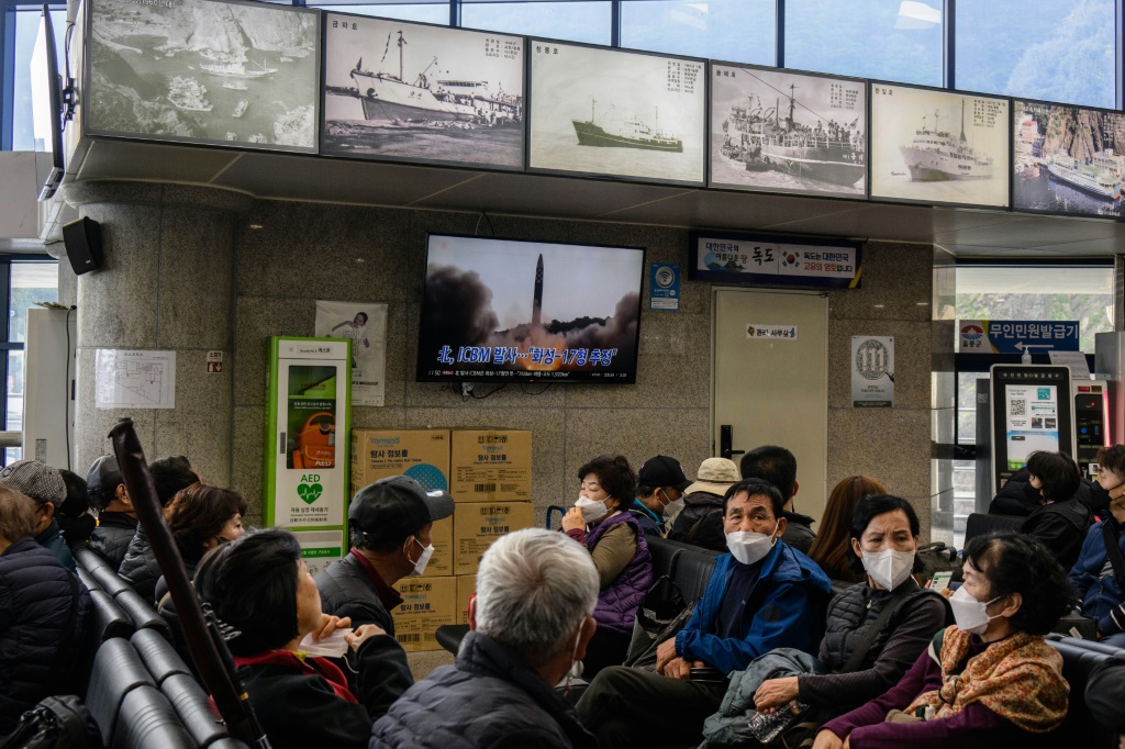 A Friday news broadcast shows file footage of a North Korean missile test as visitors wait at the ferry terminal for South Korea's eastern island of Ulleungdo