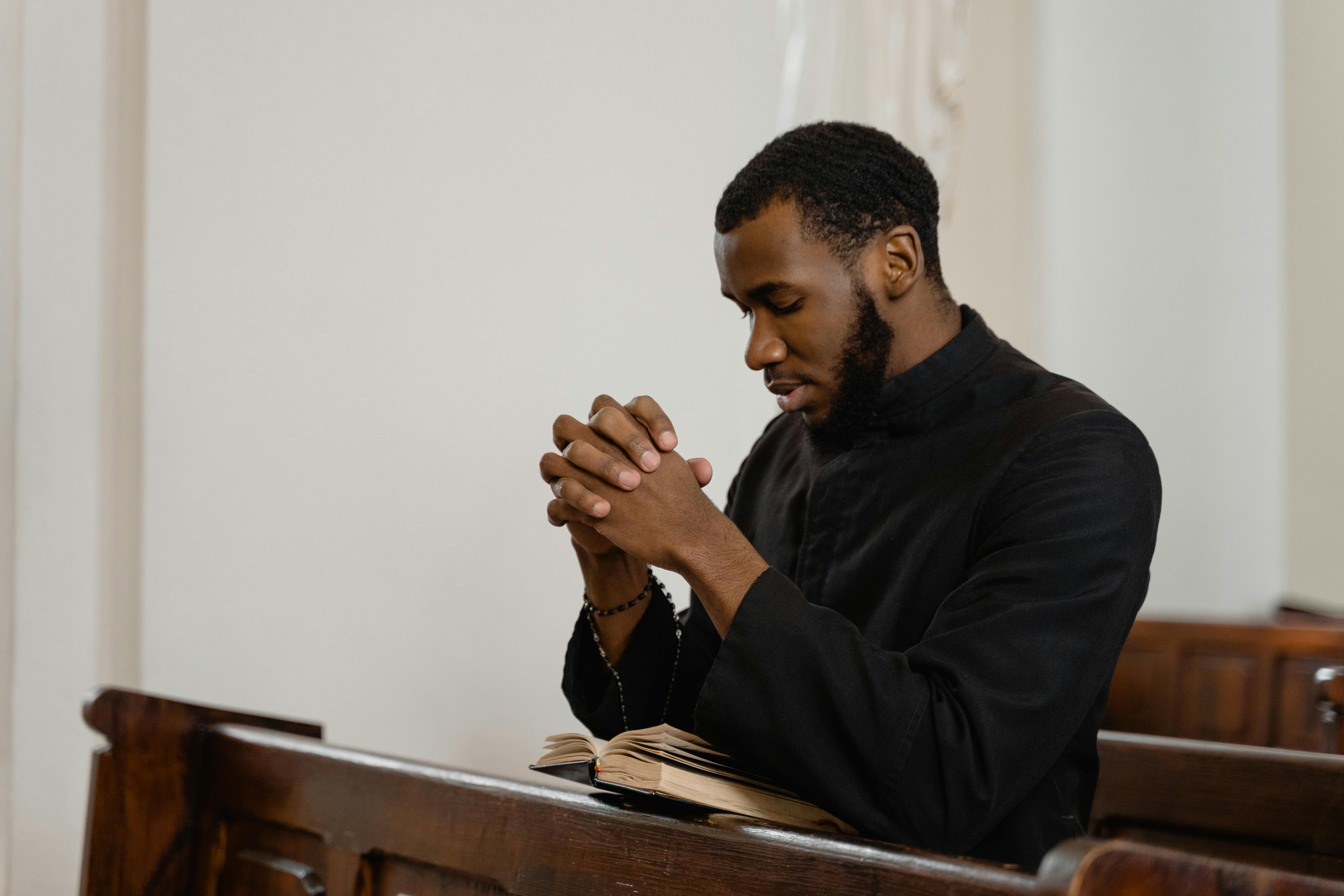 A religious man in black shirt praying solemnly