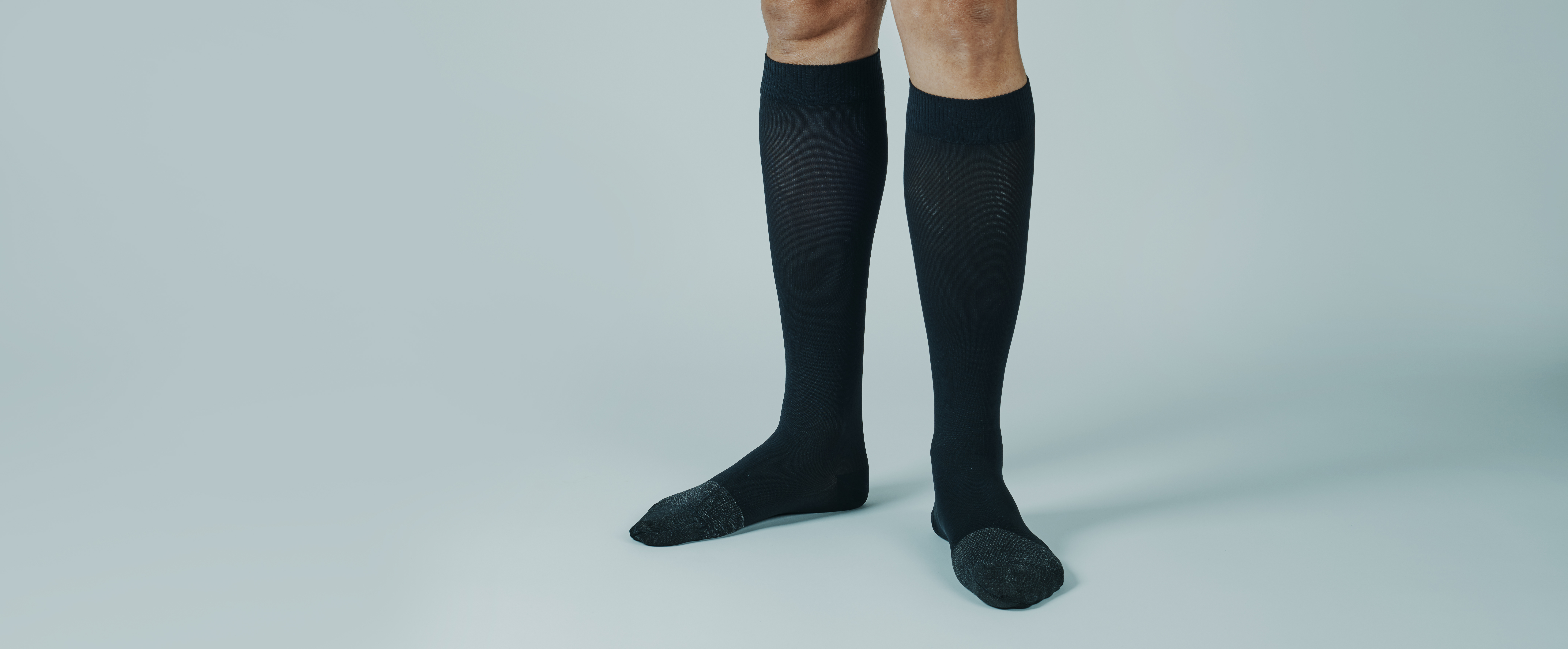 A person with black compression socks and flat shoes