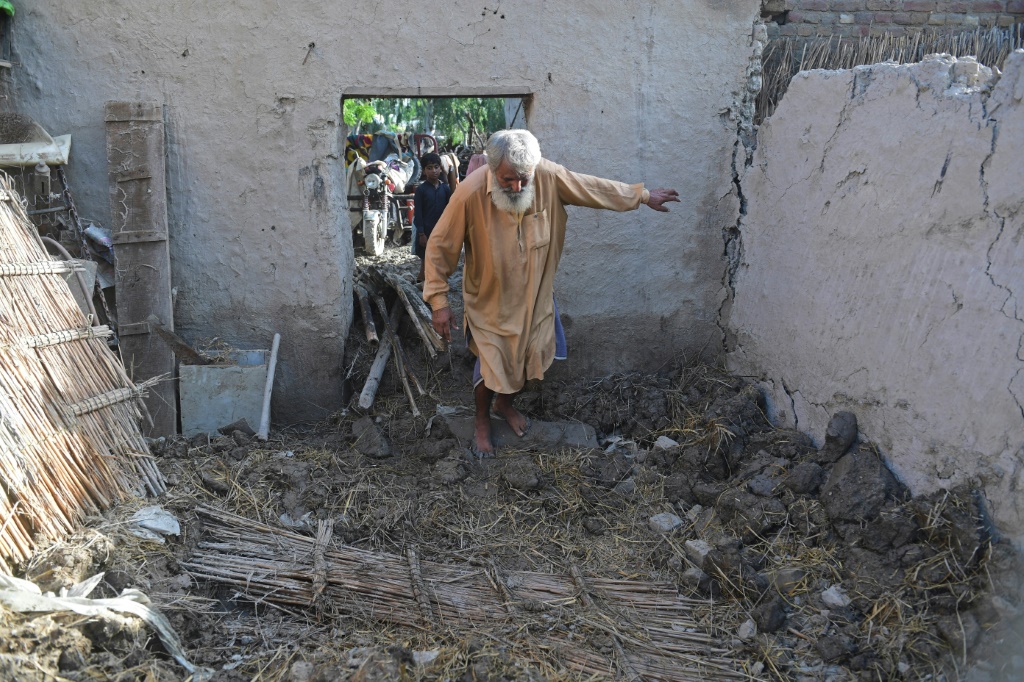 Ghulam Rasool treads through what remains of his flood-damaged mud house on the outskirts of Sukkur in Sindh province
