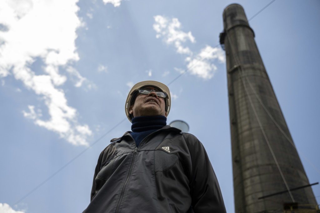 Jose Aguilar, head of human resources at the new metallurgical company, stands in front of a towering chimney, which he hopes will work for another 100 years