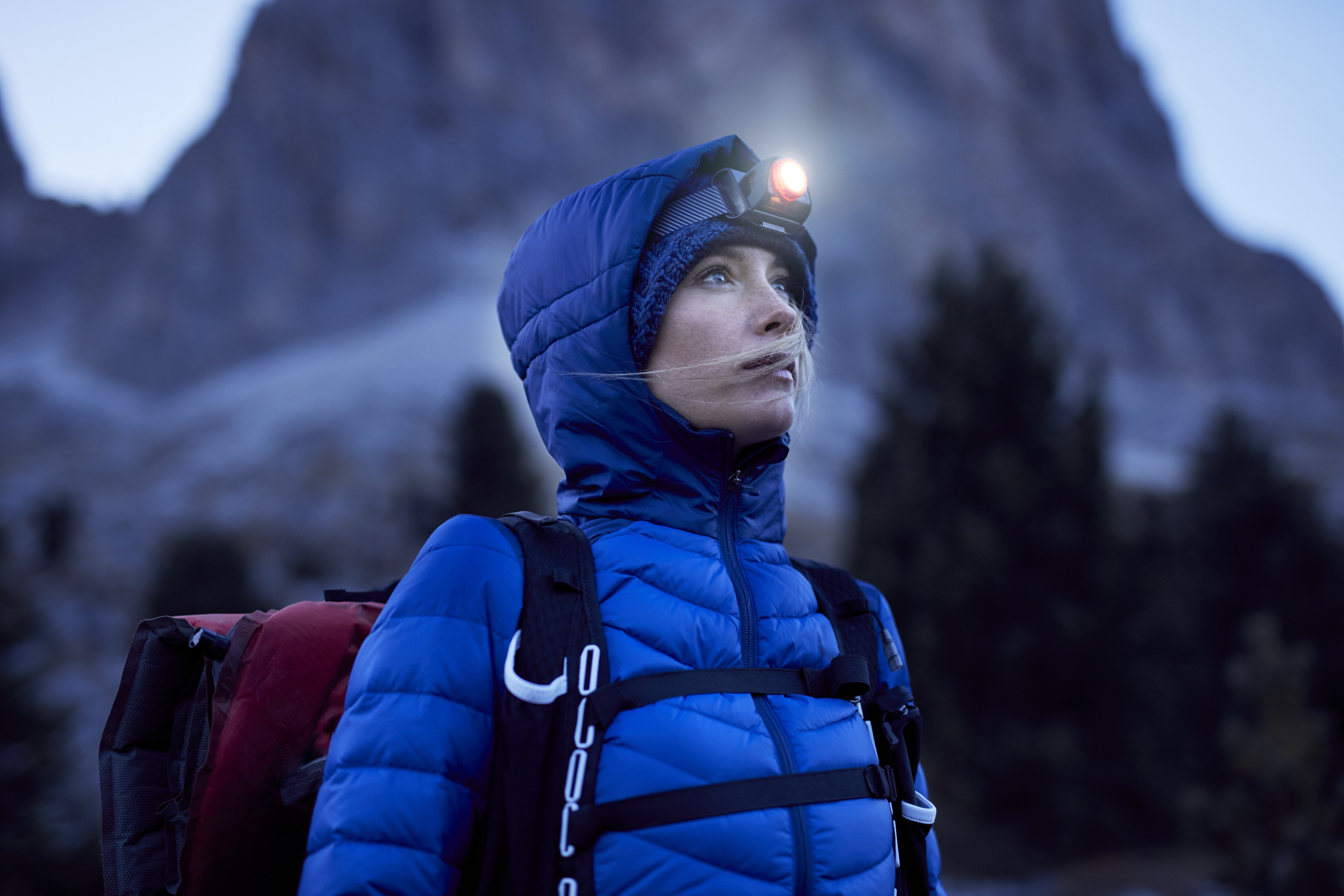 A young woman wearing a headlamp at dusk in the mountains