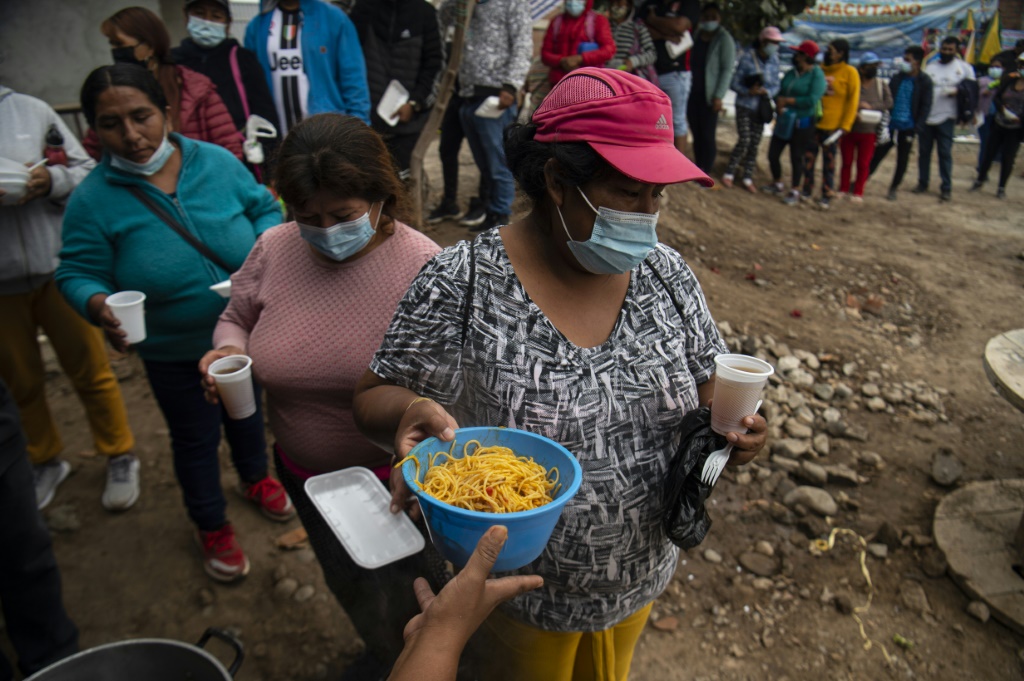 People queue for food at a soup kitchen in Peru