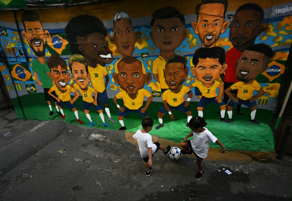 Children playing football in Rocinha in front of a mural of the national team