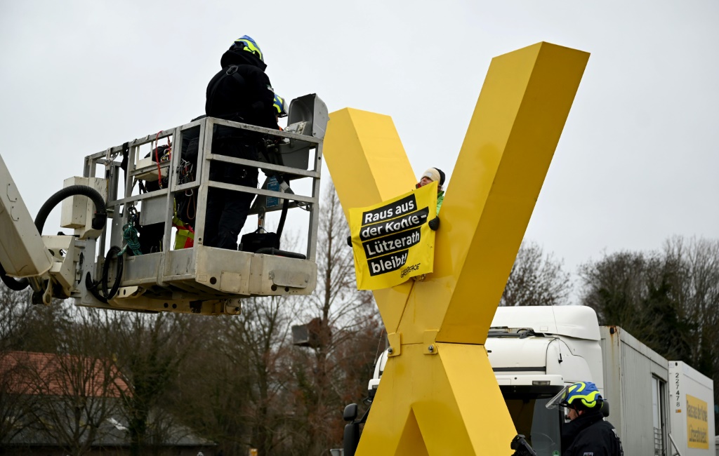 Policemen on a lifting platform prepare to remove an anti-coal activist sitting on a giant yellow X sculpture on January 10, 2023 in Luetzerath, western Germany