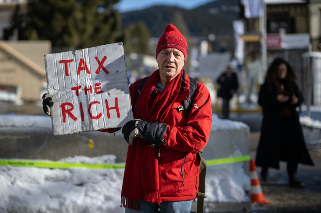 British millionaire Phil White carries protest sign "Tax the rich" outside the World Economic Forum
