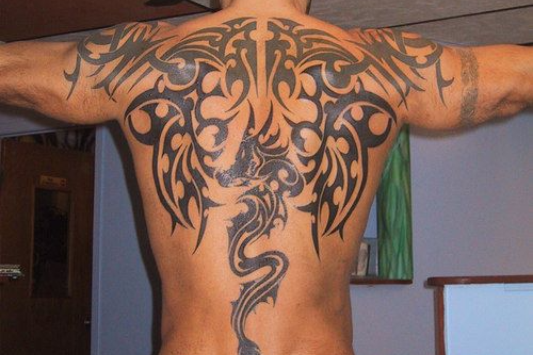 A man has an intricate black back tattoo