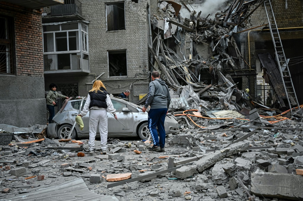 Local residents stand amid the rubble of an apartment after it was hit by a Russian missile strike in Kharkiv, Ukraine.
