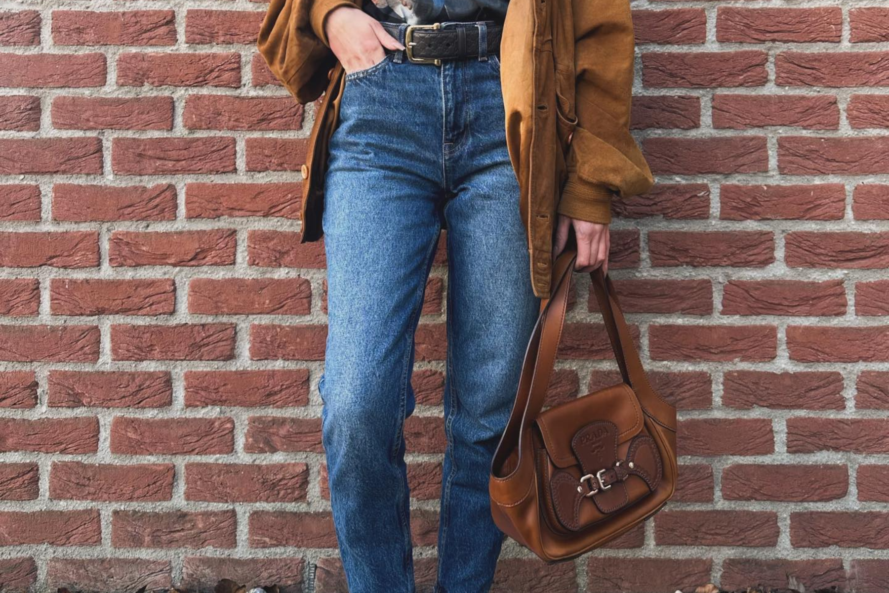 A person is rocking a blue jeans with a brown jacket and bag