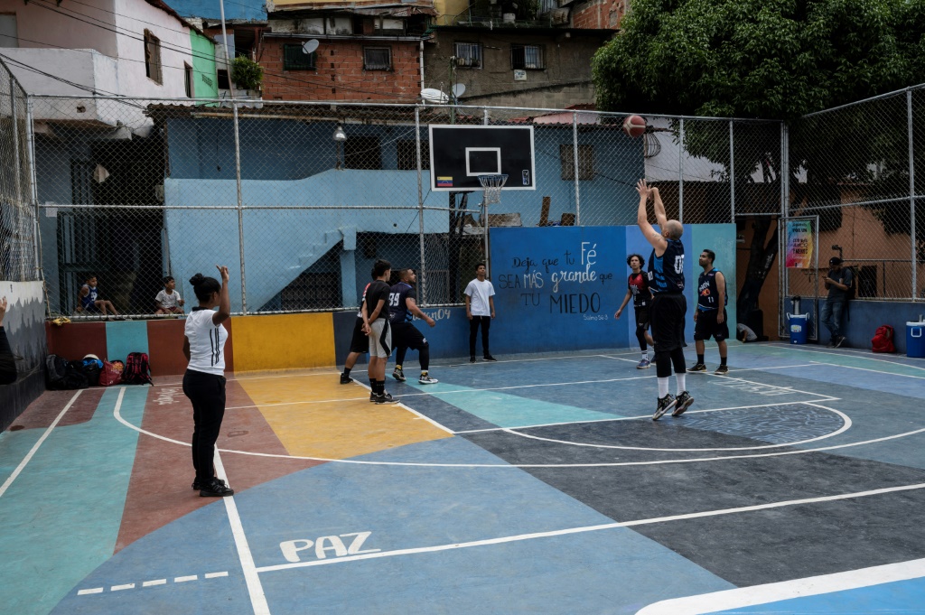 A young basketball referee trainee (L) observes a game between two local youth teams supported by the Caracas Mi Convive NGO, at Santa Eduviges neighbourhood in Caracas in August 20, 2022