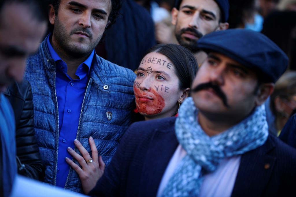A demonstrator with a red hand painted on her mouth and "Freedom" written on her forehead attends a rally in support of Iranian protests in Paris
