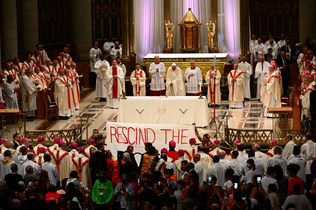 Indigenous people hold a protest banner calling for Pope Francis to rescind the Doctrine of Discovery, as he celebrates mass at the shrine of Sainte-Anne-de-Beaupre in Quebec, Canada, on July 28, 2022