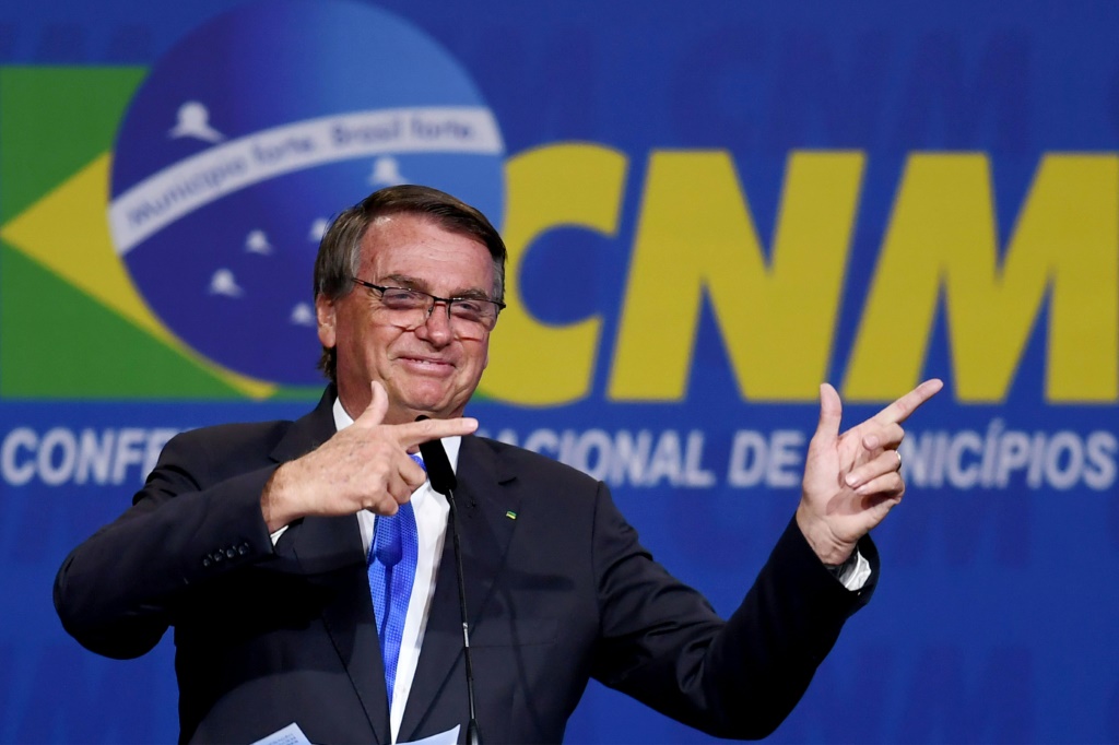 Brazilian President Jair Bolsonaro makes his signature 'pistol' gesture during an appearance in April 2022 in Brasilia