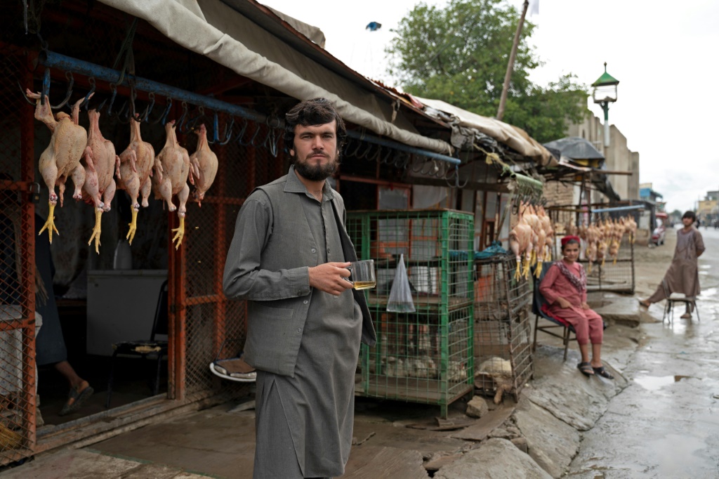 A chicken vendor drinks tea as he waits for customers in front of his shop in a market near the former US military base in Bagram