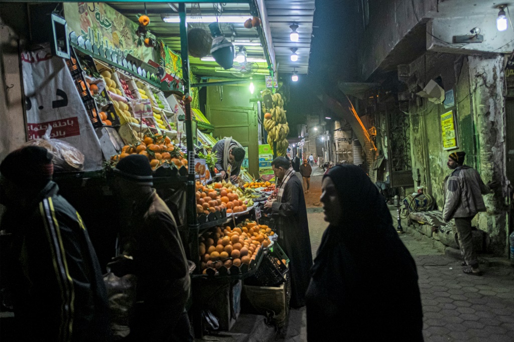 People walk past a fruit seller's stall in the Azhar district of Egypt's capital Cairo on January 16: many ordinary Egyptians are struggling amid an economic crisis