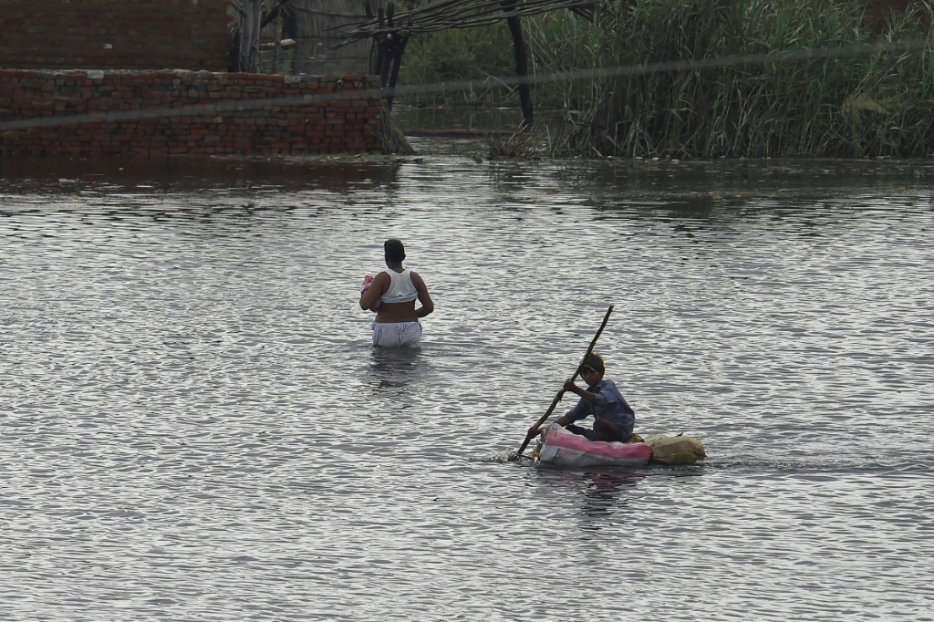 A child makes his way on a makeshift raft across flooded farmland near Sukkur, Sindh province