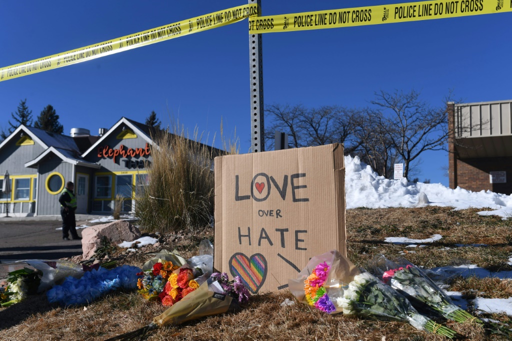 Bouquets of flowers and a sign reading "Love Over Hate" are left near Club Q following the mass shooting