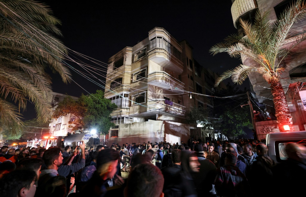 A large crowd of onlookers gathered on the street outside the multi-storey home from which plumes of smoke billowed