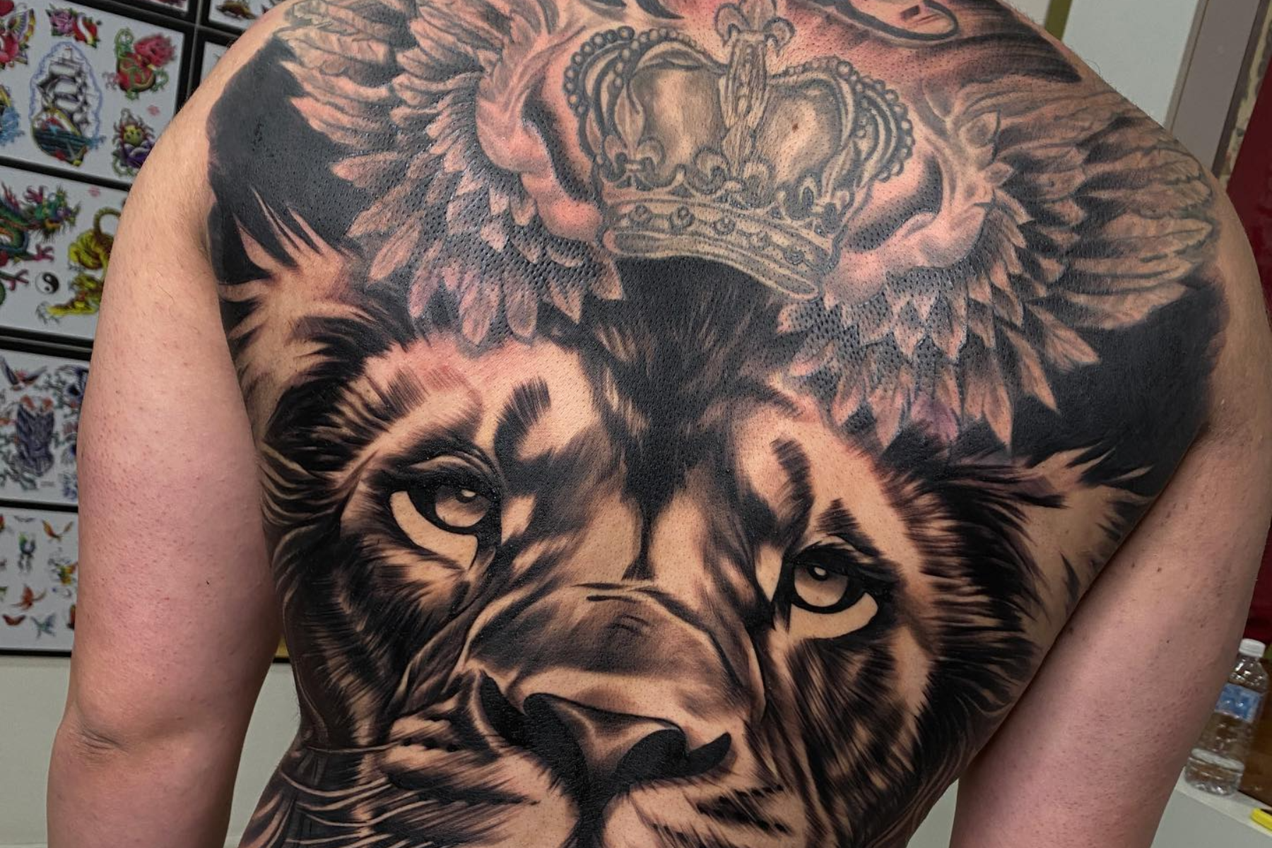 A man is having a lion head and crown tattoo