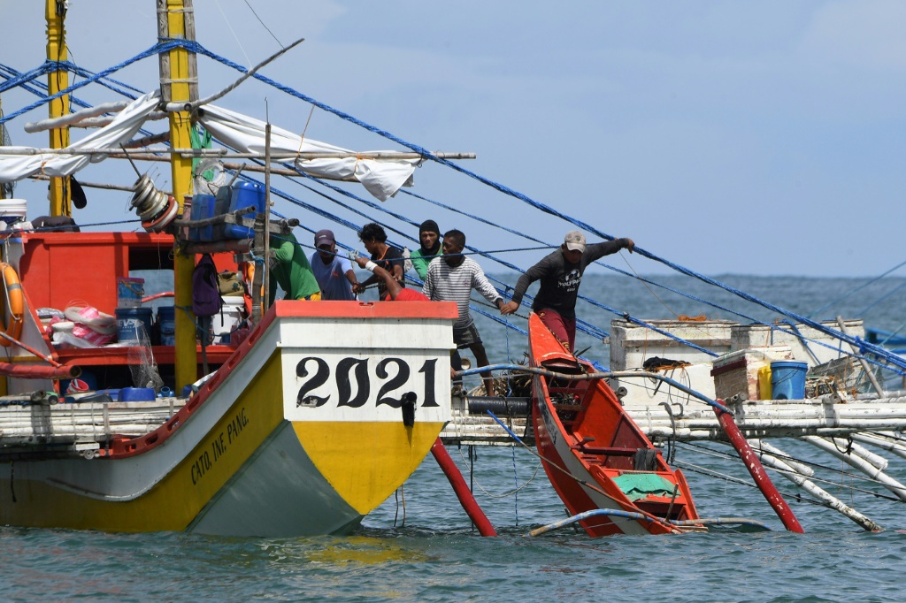 Crew members prepare to load small boats to their fishing 'mother' boat before heading into the South China Sea