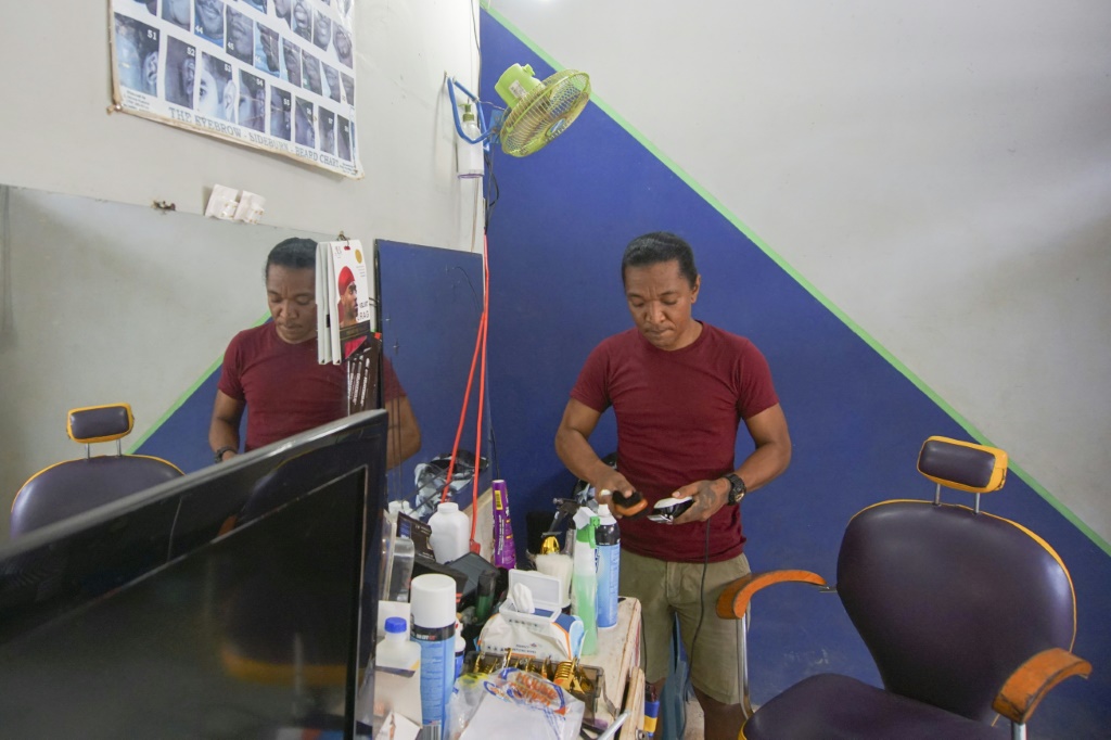 Kimtse Kimo Castello cleans his equipment at his small barber shop in Port Kaituma, Guyana