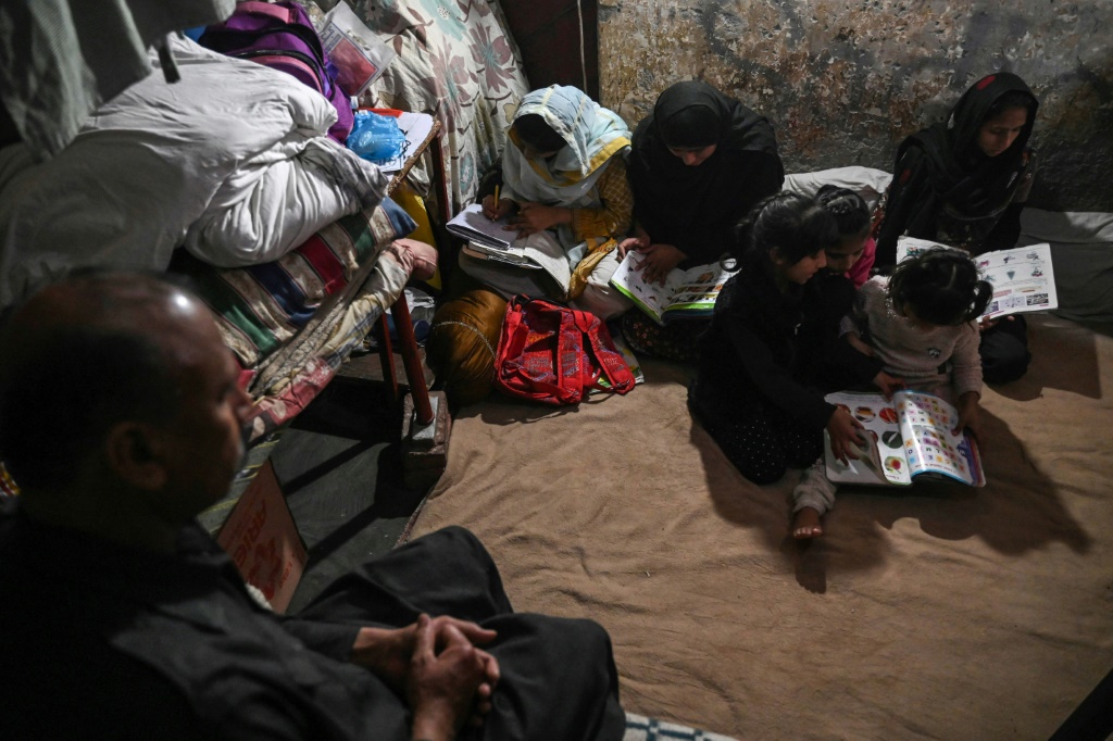 Muhammad Amin watches his daughters study at their home in Lahore, Pakistan