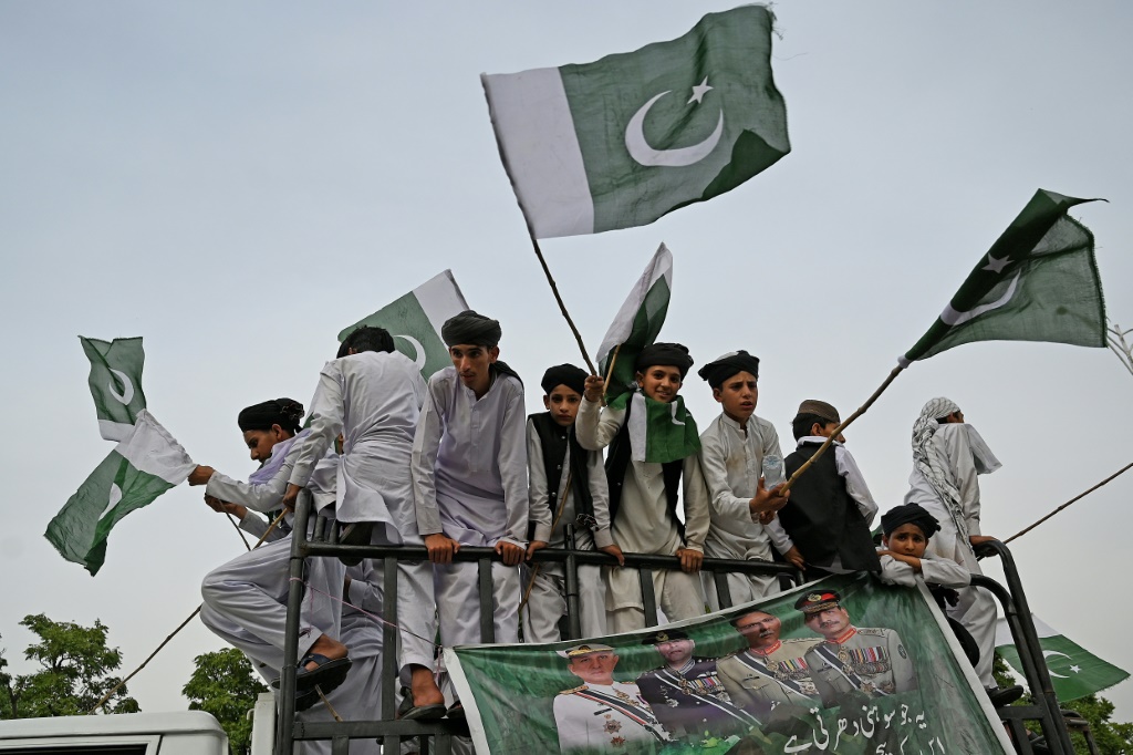 People carry flags at a rally to show solidarity with Pakistan's army in Islamabad. An economic crisis is driving Imran Khan's campaign to return to power, as ordinary people say they are unable to feed their families