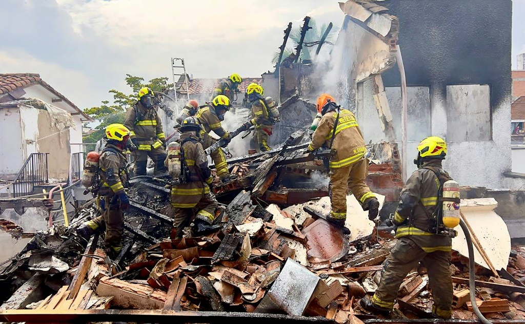 Firefighters work at the site where a light aircraft crashed, leaving eight people dead in the Belen Rosales neighborhood in Medellin, Colombia