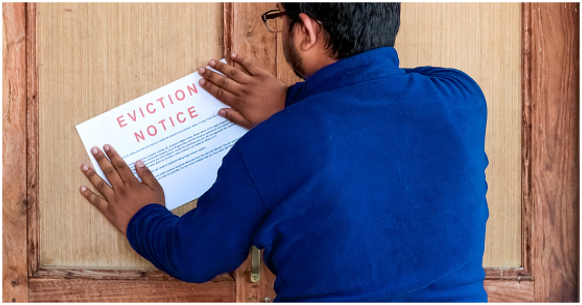 A landlord posts an eviction notice on the door of his tenant
